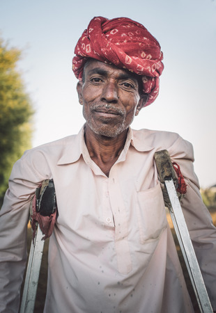 GODWAR REGION, INDIA - 12 FEBRUARY 2015: Rabari tribesman in field with crutches. Post-processed...
