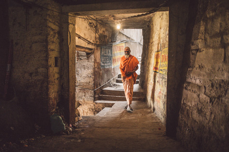 VARANASI, INDIA - 20 FEBRUARY 2015: A sadhu walks through a passage.  In Hinduism, a sadhu is a religious ascetic or holy person. Post-processed with grain, texture and colour effect.のeditorial素材