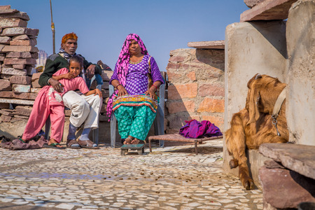 JODHPUR, INDIA - 09 FEBRUARY 2015: Grandparents rest with granddaughter on roof terrace of home with goat sitting close by.のeditorial素材