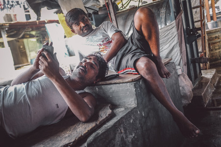 MUMBAI, INDIA - 08 JANUARY 2015: Indian workers take a rest after an early morning shift in Dhobi ghat. Post-processed with grain, texture and colour effect.のeditorial素材
