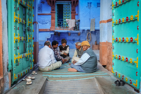 JODHPUR, INDIA - 07 FEBRUARY 2015: Five elderly men sitting on ground in gateway of courtyard and playing cards in old part of Jodhpur, referred to as "Blue City" due to the vivid blue-painted houses.のeditorial素材