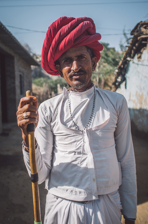 GODWAR REGION, INDIA - 13 FEBRUARY 2015: Rabari tribesman stands in courtyard of home wearing traditional clothes and holds herding stick. Rabari or Rewari are an Indian community in the state of Gujarat.のeditorial素材