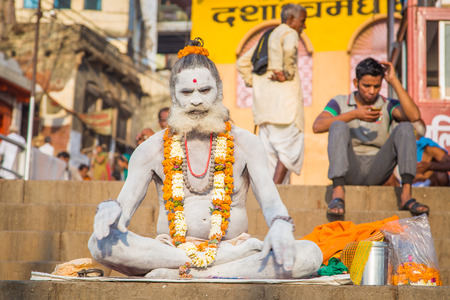 VARANASI, INDIA - 23 FEBRUARY 2015: Sadhu sits on ghat with legs crossed. Sadhu is a religious ascetic or holy person.のeditorial素材