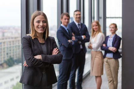 Corporate portrait of young business woman with her colleagues in background.