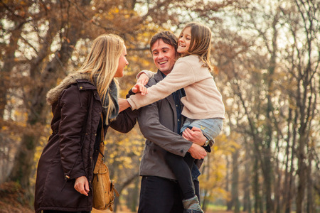 Playful family of three walk in a park on an autumn day.の写真素材
