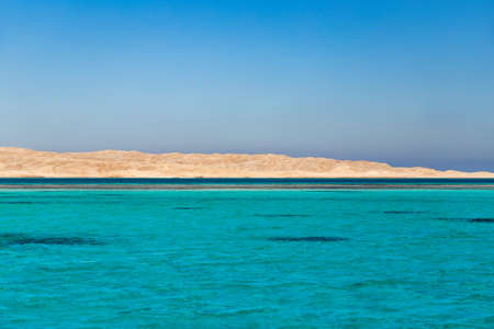 Amazing turquoise clear sea with desert in the background.の写真素材