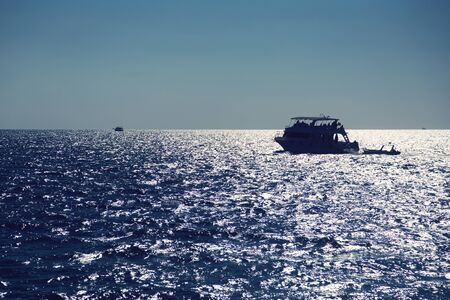 Silhouette of boat on a sea horizon.の写真素材