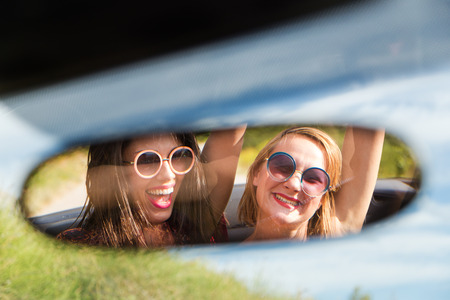 Two happy girls in a car rear-view mirror.の写真素材