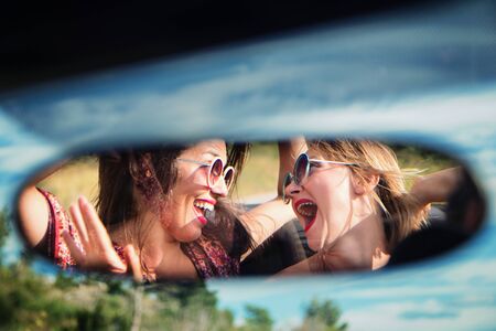 Two happy girls in a car rear-view mirror.の写真素材