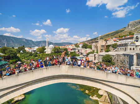 MOSTAR, BOSNIA AND HERZEGOVINA - AUGUST 10, 2016: Two guys surrounded with tourists preparing to jump in Neretva river form Old Bridge.のeditorial素材