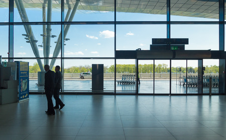 ZAGREB AIRPORT - 24 APRIL 2017: Businessmen walking in front of glass door entrance.のeditorial素材