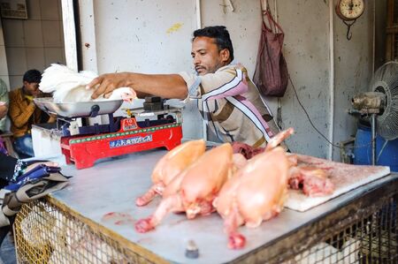 MUMBAI, INDIA - JANUARY 2015: Street salesman weights live chicken on scale at meat stand.のeditorial素材