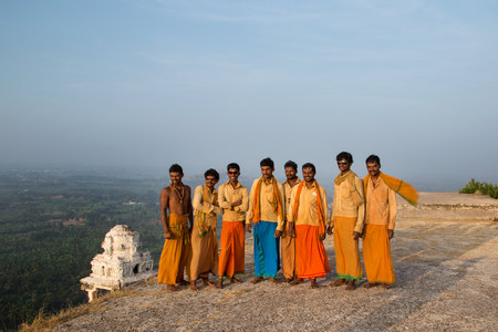 HAMPI, INDIA - 03 FEBRUARY 2015: Eight pilgrims gather for a photo on hilltop dressed in orange clothes.のeditorial素材