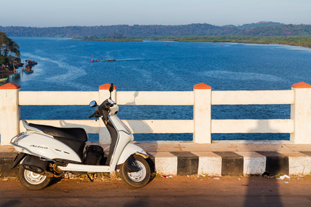 White scooter parked on the road at sunset in Goa.のeditorial素材