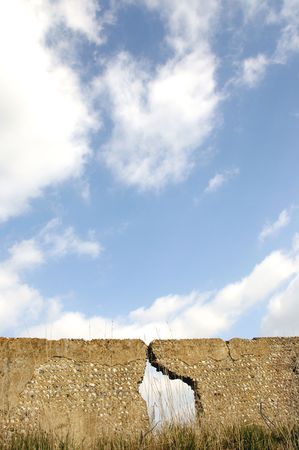 a old flint wall with a large crack in it. With blue skyの写真素材