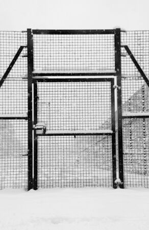 Black metal gate in the snowの写真素材