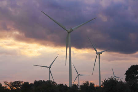 windmills on a hill at sunset with cloudsの写真素材