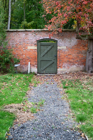 Green garden door at the end of a gravel path within a walled gardenの写真素材