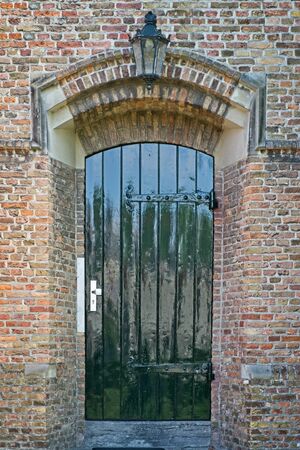 Green door in an old brick wall with lampの写真素材
