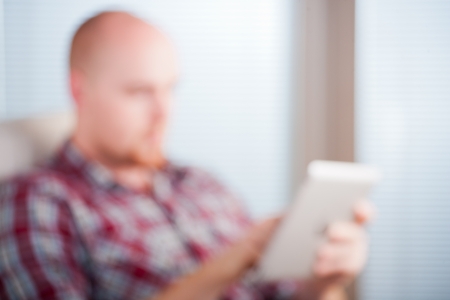 Focused man working and playing with tablet computer  lots of copyspace, unfocused image, backgroundの写真素材