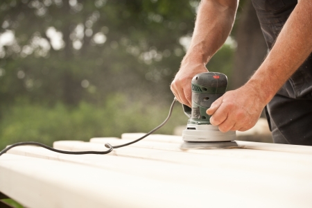 Closeup of a handyman  carpenter s hand sanding a wood with sanderの写真素材
