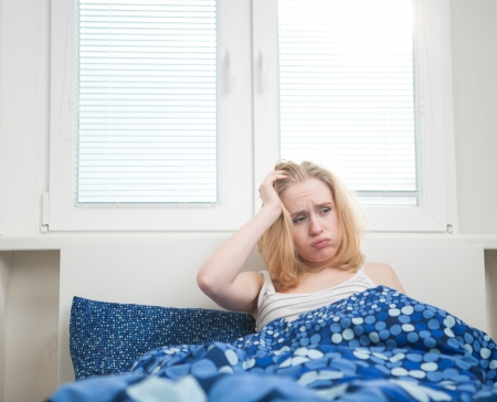 caucasian woman in bed, getting up late to work with terrible hangover, funny conceptの写真素材