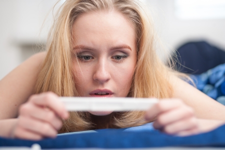 beautiful young woman in the bedroom worrying because of the pregnancy test result の写真素材