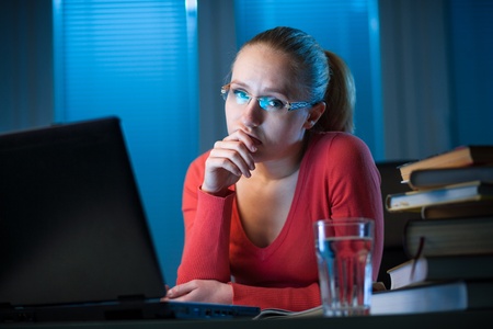 young bored female college student studying poorly at late evening before exam, funny night procrastination conceptの写真素材