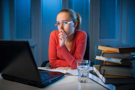 young bored female college student studying poorly at late evening before exam, funny night procrastination conceptの写真素材