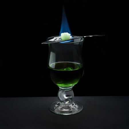 absinth shot served in bohemian way (with flaming sugar on top) on black backgroundの写真素材