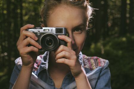 portrait of a young pretty woman looking through a vintage looking rangefinder camera