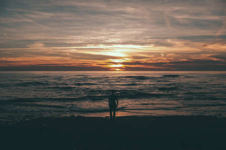 woman standing and looking at the sunset and the seaの写真素材
