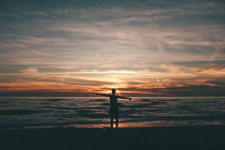 woman standing and looking at the sunset and the seaの写真素材