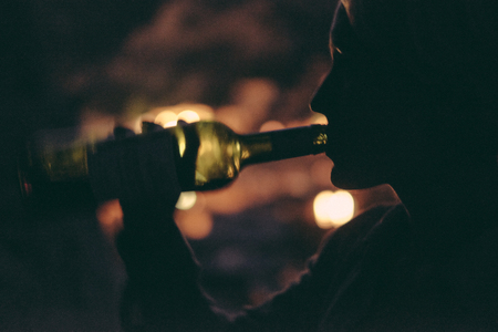 woman drinking wine at night, right from the bottleの写真素材
