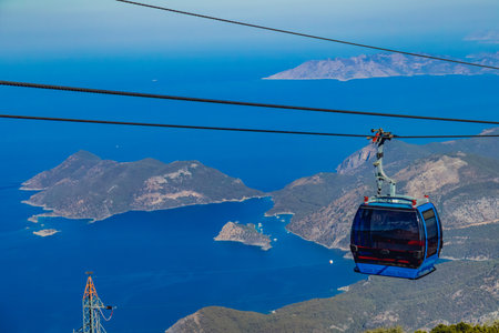 Cable car cabin in the mountains against the blue sea and coast on a sunny summer dayの写真素材