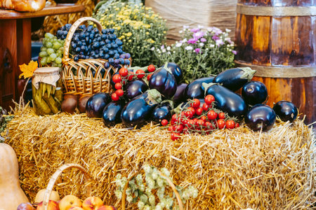 fresh vegetables, fruits and preservation arranged on straw and in basket against a background of flowers, crate and wooden barrelの写真素材
