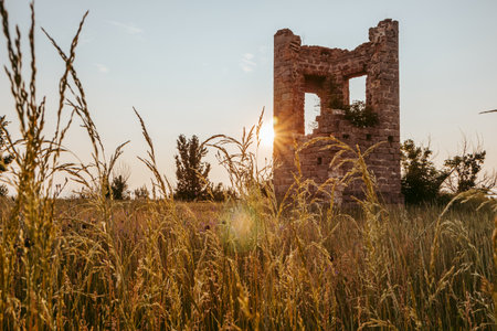 ruins of a tower in a field at sunset on a summer dayの写真素材