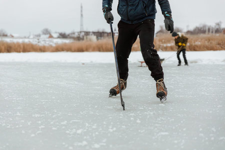 A man with a stick and skates plays hockey, close-up of his legsの写真素材
