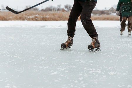 A man with a stick and skates plays hockey, close-up of his legsの写真素材