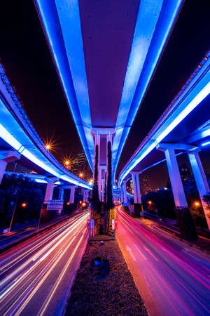 Abstract cityscape traffic with motion blur. Moving through modern city street with neon illuminated bridges.の写真素材