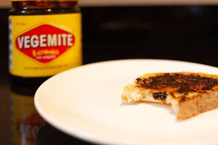 Sydney, Australia - November 2, 2019 - Vegemite and butter on sough dough toast with bite with Vegemite jar in the background. An classic icon Australian spread.のeditorial素材
