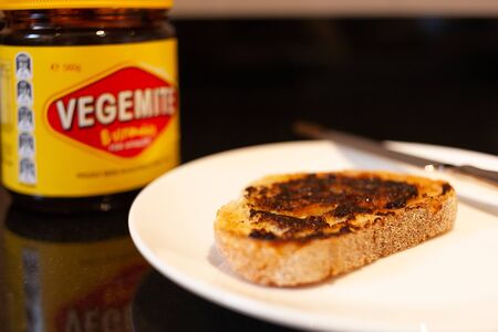 Sydney, Australia - November 2, 2019 - Vegemite and butter on sough dough toast, knife and Vegemite jar. An classic icon Australian spread.のeditorial素材
