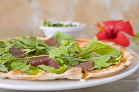 Meat pizza with a green salad toppingの写真素材