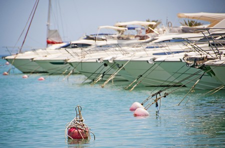 Private motor yachts moored in a tropical marina with a mooring buoy in the foregroundの写真素材