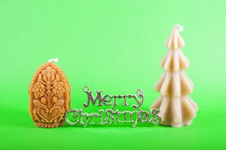 Silver merry christmas sign with two christmas candles isolated on greenの写真素材