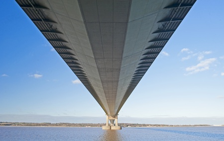 Large suspension bridge spanning a wide river on a clear day