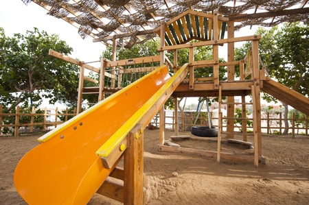 Childrens wooden climbing frame with slide in a playground at parkの写真素材