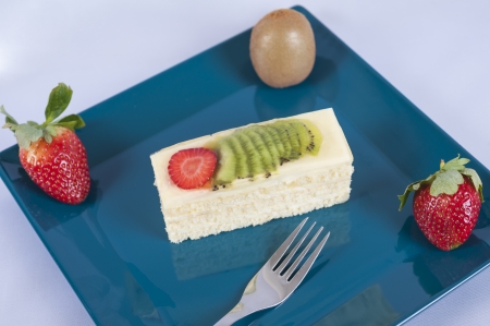 Sponge cake with strawberry and kiwi fruit on a blue plateの写真素材
