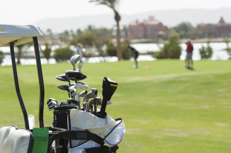 Closeup detail of golf clubs in a bag with golfers on the green in backgroundの写真素材