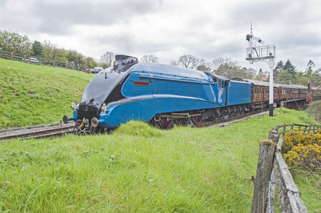 Old english steam train traveling along tracks through rural countryside sceneryのeditorial素材